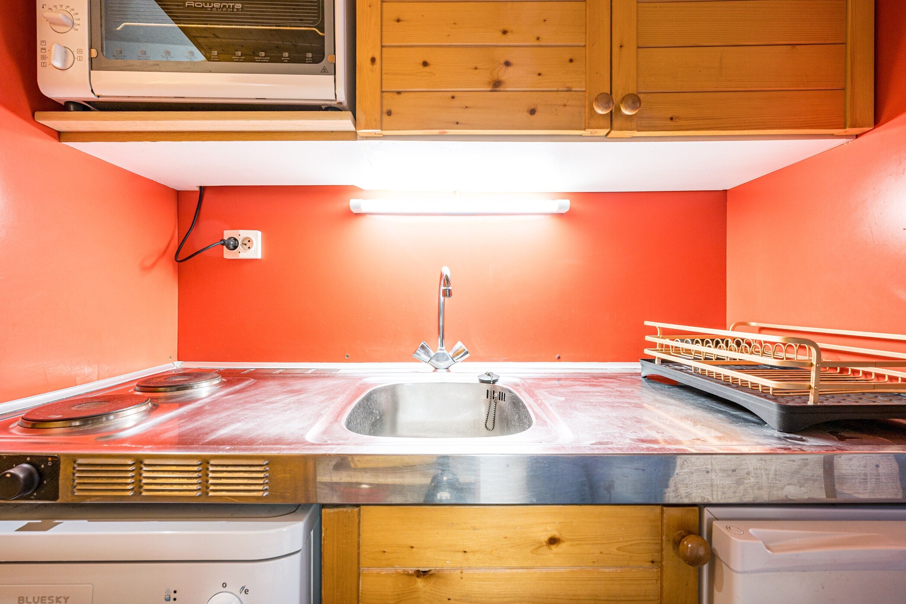 Una cocina compacta con un lavabo, estufa y armarios de madera.
