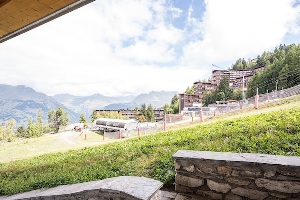 A mountainous landscape with a stone wall and a building with multiple balconies.