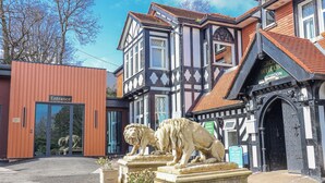 A building with a reception area, a lion statue, and a sign indicating a holiday booking office. - Woodlands Platinum (Ruthin)