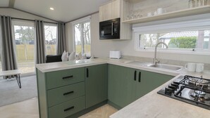Une cuisine moderne avec des meubles de couleur verte, un four à micro-ondes, une cuisinière à gaz et une fenêtre donnant sur un jardin.