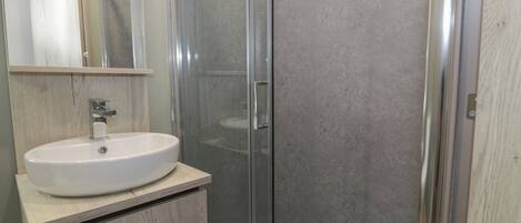 A bathroom with a white sink, a mirror, and a glass-enclosed shower area.