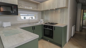 Une cuisine moderne avec des meubles de couleur verte, un four à micro-ondes, un évier et une cuisinière.