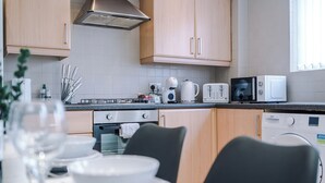 A modern kitchen with wooden cabinets, a stainless steel range hood, a microwave, a toaster, and a dishwasher.