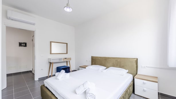 Une chambre d’hôtel avec un grand lit, un bureau, une table de chevet et une armoire.