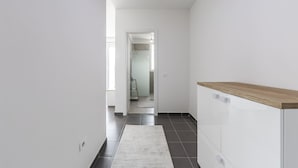Un couloir avec un comptoir en bois, un tapis et une vue sur une autre pièce.