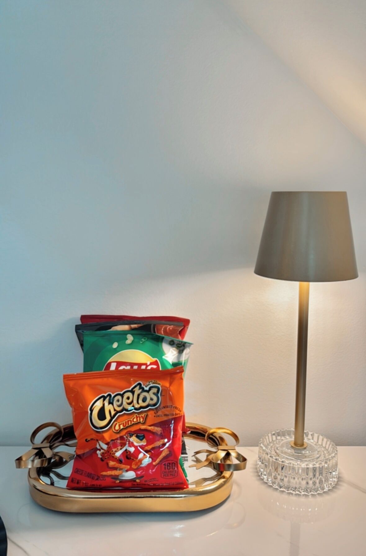 A tray with three bags of Cheetos snacks and a lamp on a table.
