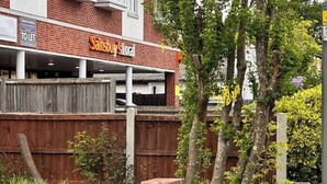 Ein Gebäude mit einem 'Sainsbury's Local'-Schild, einer Ziegel-Fassade und einem Holzzaun.
