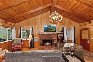 Una sala de estar acogedora con chimenea, paredes de madera, un televisor y asientos cómodos.