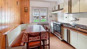 Cozinha com paredes de madeira, mesa de jantar com cadeiras, janela com vista e forno embutido.