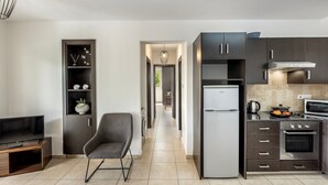 A modern kitchen with dark cabinetry, a built-in oven, and a refrigerator.