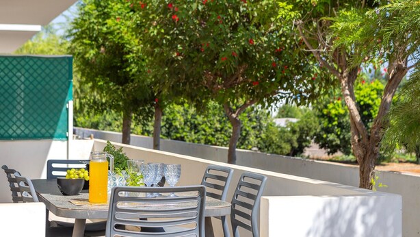 An outdoor seating area with a table, chairs, and a glass of orange juice.