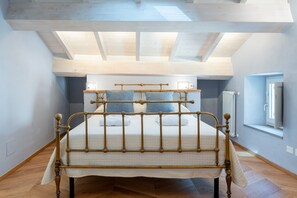 Ein Schlafzimmer mit Bett, Holzboden, Dachfenster und einem Fenster.