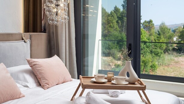 A bedroom with a bed, pillows, a tray with tea set, and towels.