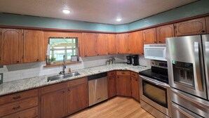 A kitchen with wooden cabinets, a stainless steel refrigerator, a microwave, and a dishwasher. - Charming 4-bedroom Country Home near Canton, TX (Edgewood)
