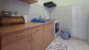 Cucina con mobili in legno, un fornello e un cestino.