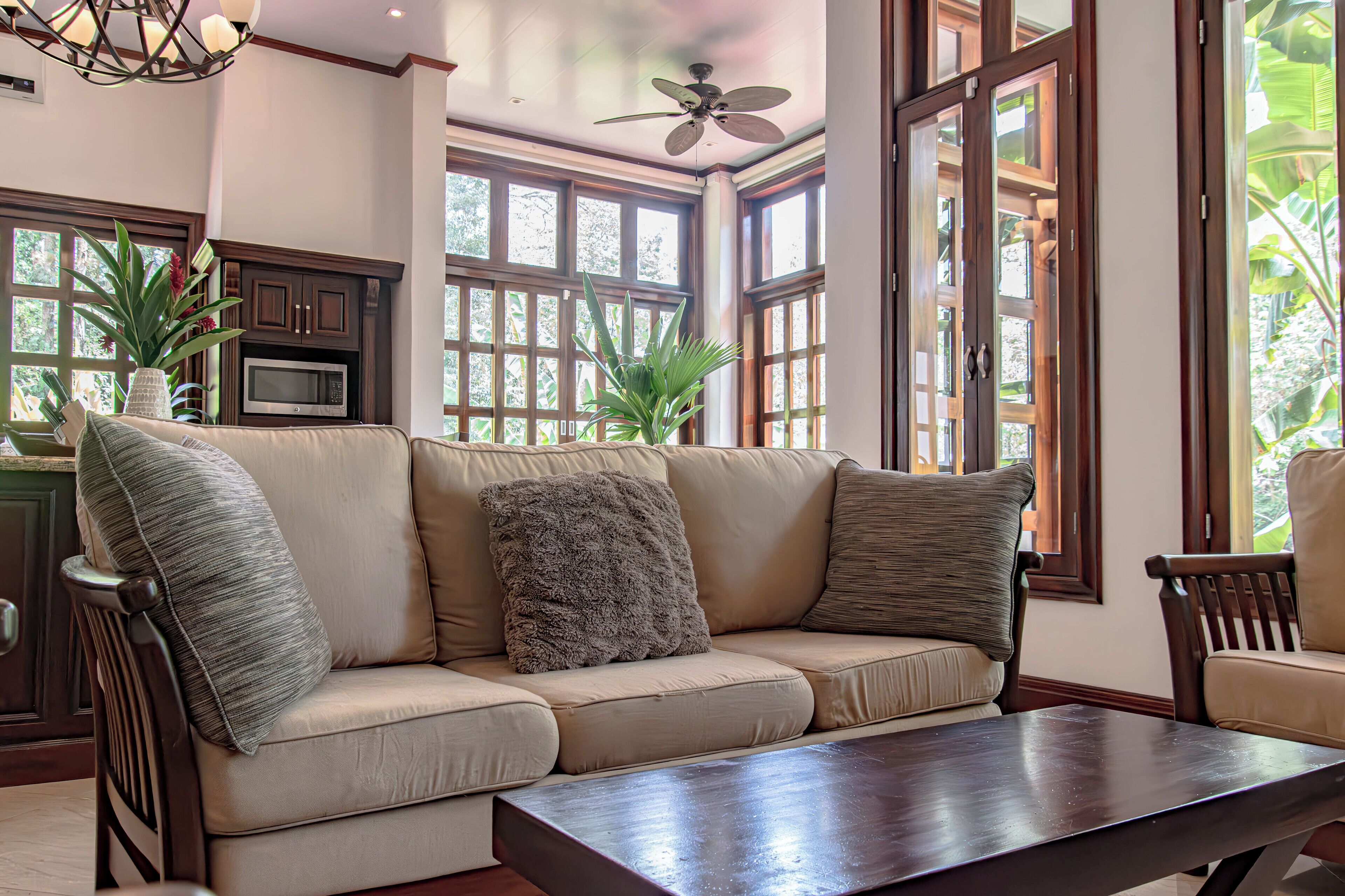 Una sala de estar acogedora con un sofá modular, una mesa de centro de madera y grandes ventanales con vistas al exterior.