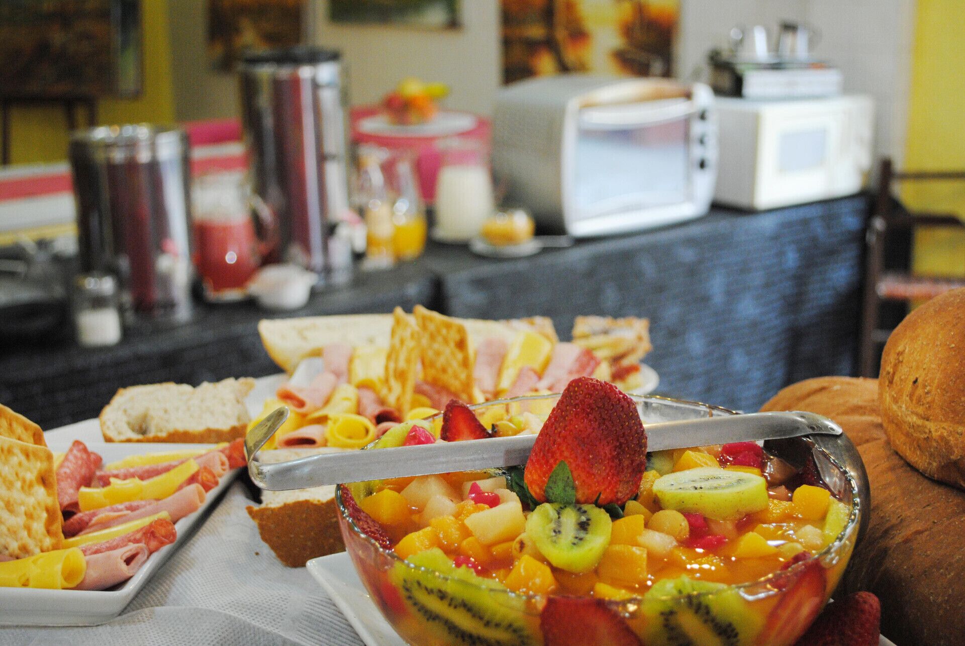Een ontbijtbuffet met diverse soorten eten, waaronder fruit, brood en gebak.