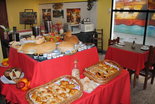 A buffet table with various breads, pastries, and condiments. - Hotel Ibiza (Villa Gesell)