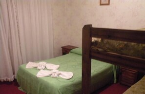 A single bed with a green bedspread and a wooden headboard. There are towels placed on the bed. - Hotel Ibiza (Villa Gesell)