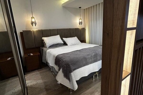 Une chambre à coucher moderne avec un grand lit, deux tables de chevet et une tête de lit.