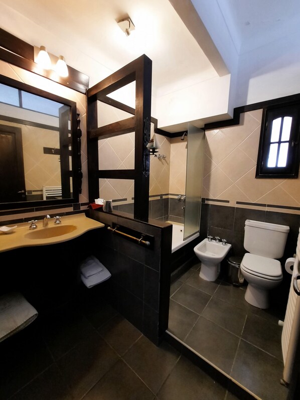 A modern bathroom with a large mirror, a sink, a toilet, and a bidet. - Posada la Villa (Villa Carlos Paz)