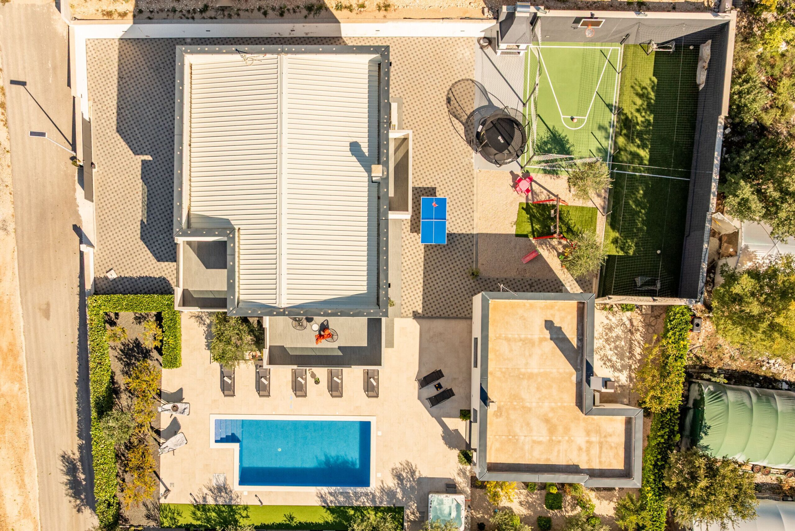 Vista aérea de una propiedad con piscina, cancha de tenis y terraza techada.