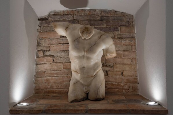 A sculpture in a niche with a brick wall background. - Palazzo Salvecchio (Bergamo)