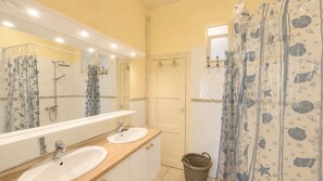 Une salle de bain avec deux lavabos, une douche, un miroir et un porte-serviettes.