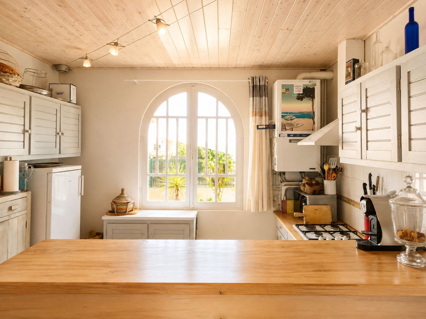 Een keuken met een groot raam, houten kastjes en een houten aanrecht.