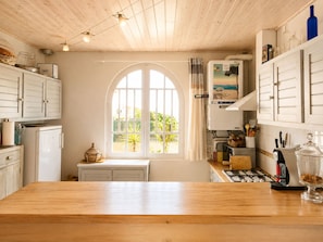 Une cuisine dotée d’une grande fenêtre, de meubles de rangement en bois et d’un plan de travail en bois.