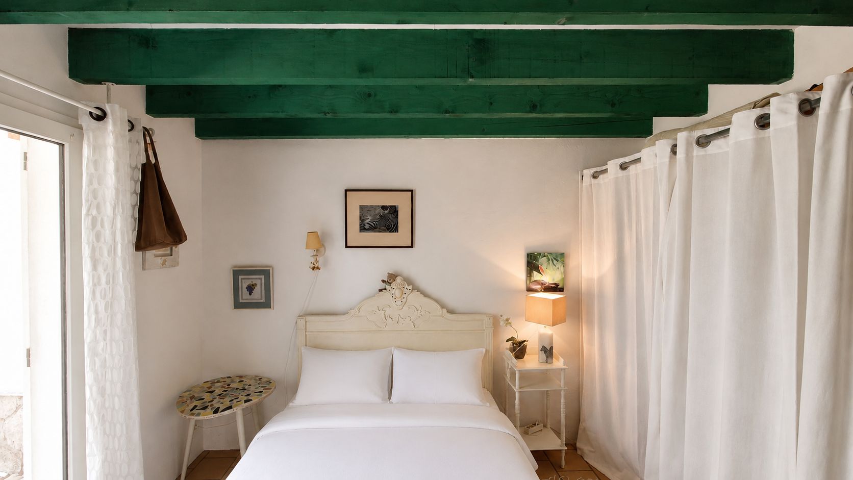 Un dormitorio con cama, mesita de noche, lámpara de pared y un marco de fotos.