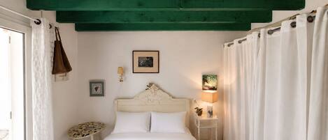 Un dormitorio con cama, mesita de noche, lámpara de pared y un marco de fotos.