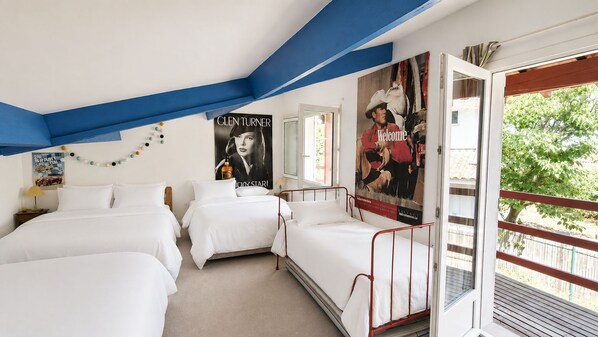 Habitación de hotel con dos camas, un cartel grande de un vaquero y un balcón con vistas a la vegetación.