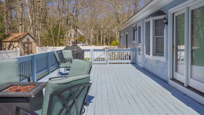 A deck with outdoor furniture, a grill, and a view of a house with a screened porch. - 141 Harlow Road (Sandwich)