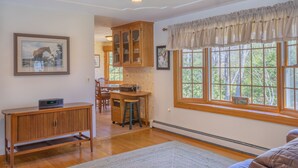 A well-lit room with wooden cabinets, a desk, and a large window with a view of trees. - 141 Harlow Road (Sandwich)