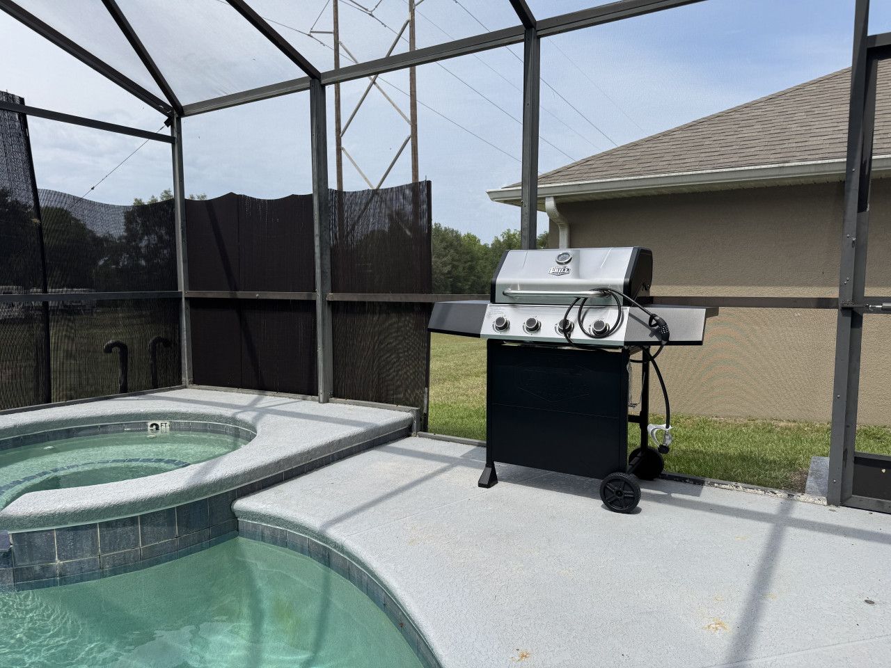 A backyard with a hot tub and a grill.