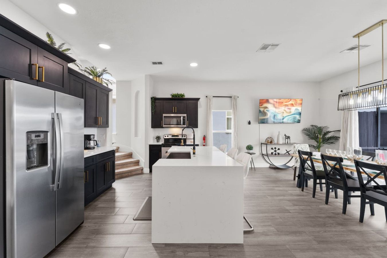 Una cocina moderna con una isla central, electrodomésticos de acero inoxidable y muebles de color oscuro.