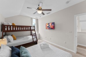 Ein Schlafzimmer mit zwei Etagenbetten, einem Deckenventilator, einem Gemälde und einer Tür.