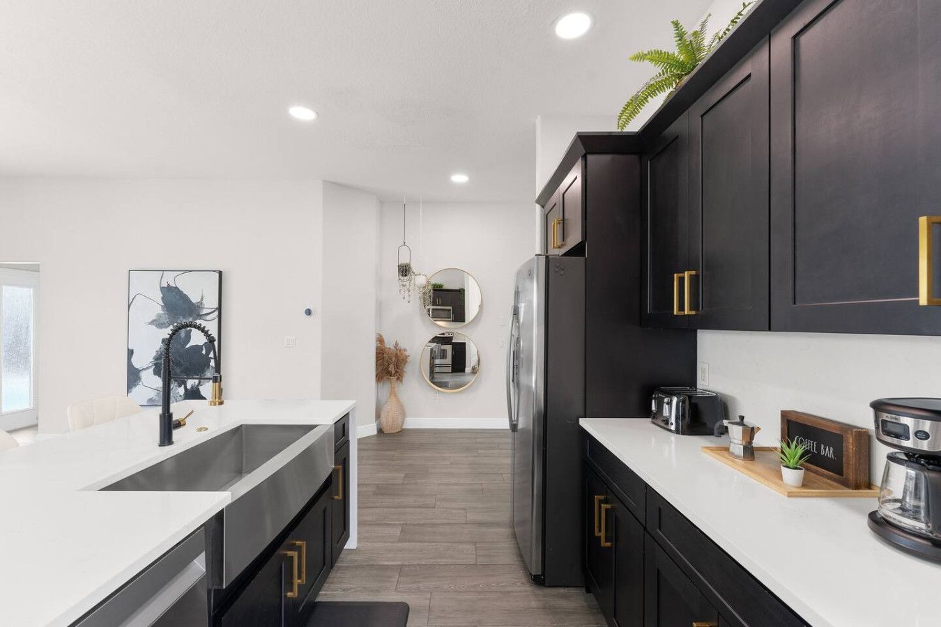 Una cocina moderna con una isla grande, armarios oscuros y una zona para preparar café.