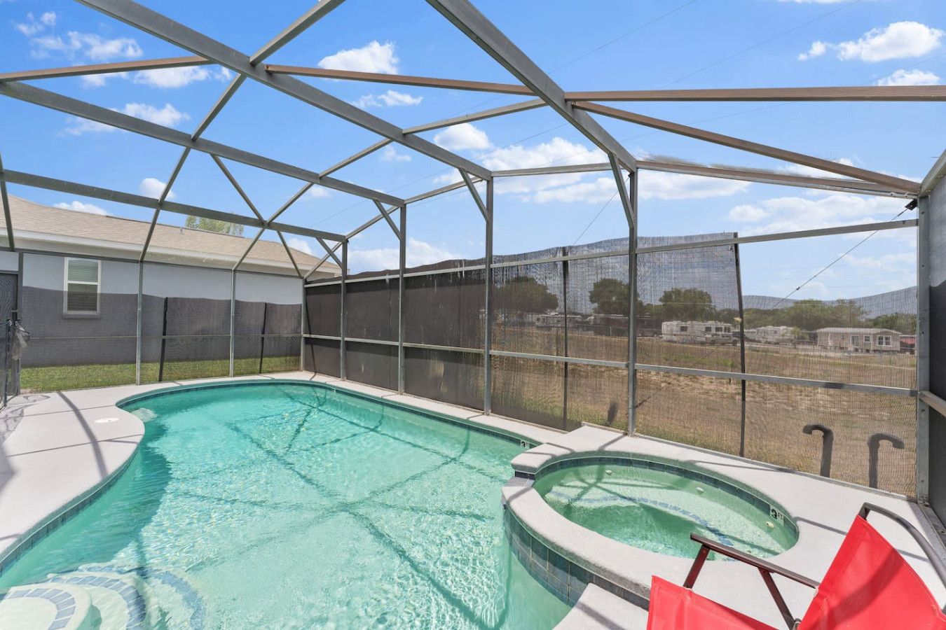 A covered swimming pool with a view of a fenced area and a building in the background.