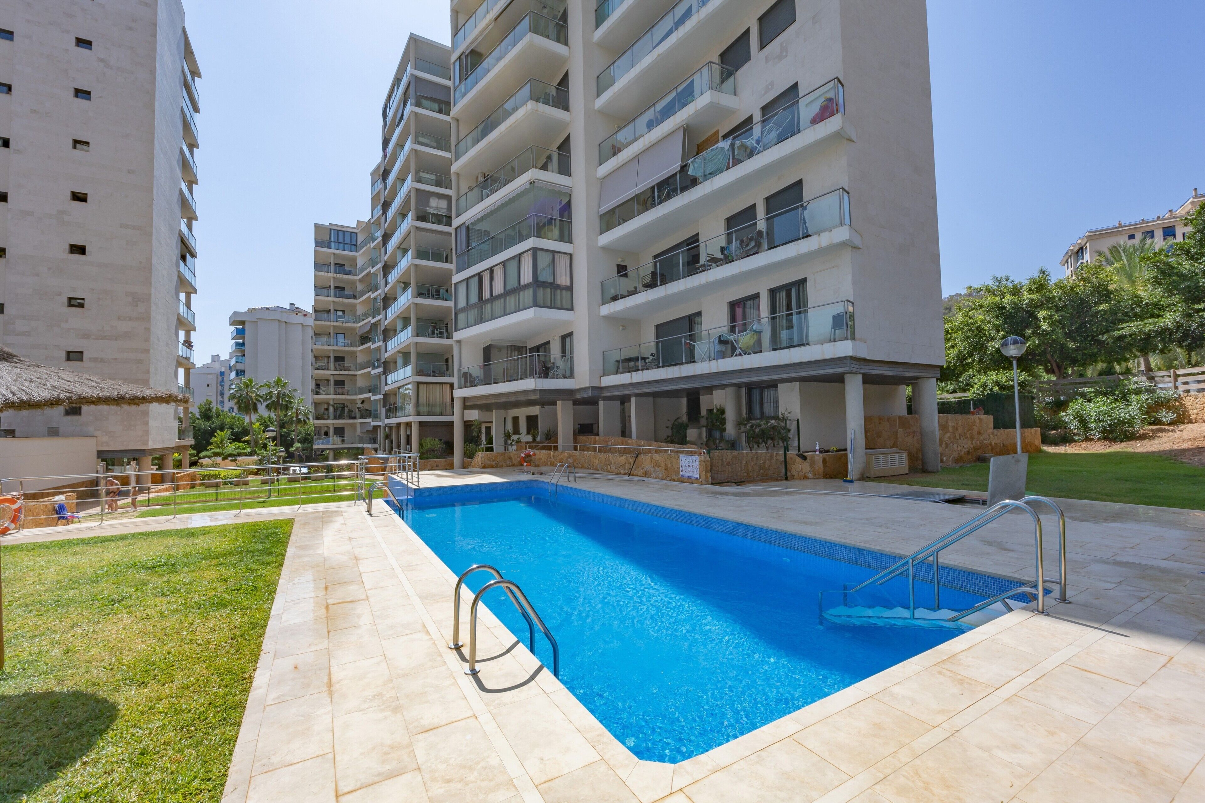 Een modern appartementencomplex met een zwembad, balkons en een verzorgd gazon.