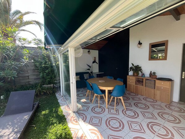 An outdoor patio with a dining table and chairs, surrounded by a wooden cabinet and a mirror on the wall. - Basque family home, 5 minutes from the Chambre d'Amour (Anglet)