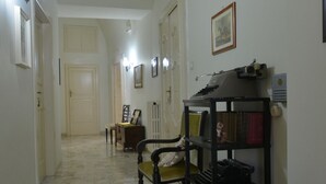 A hallway with a wooden chair, a shelf with books, and a framed picture on the wall.