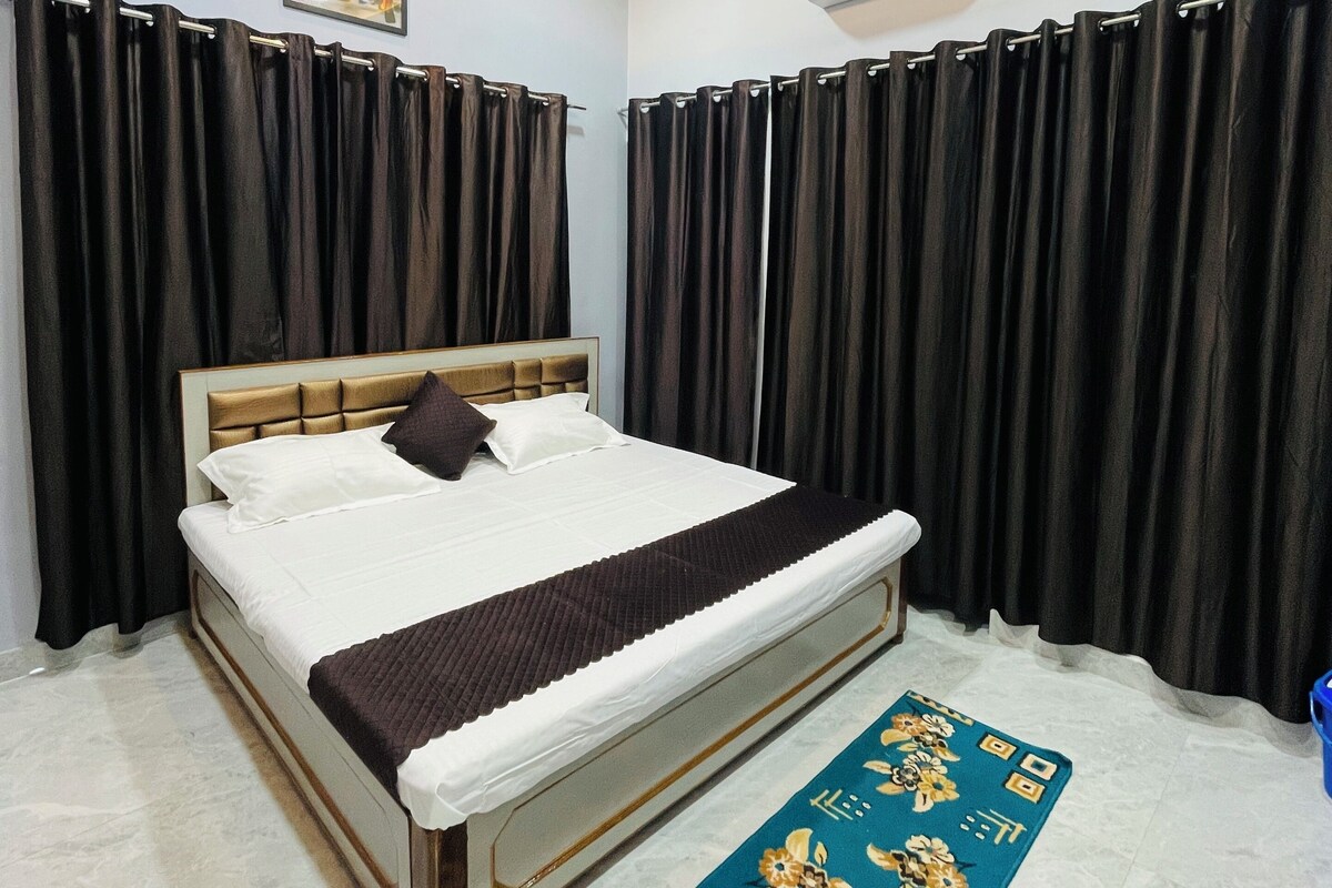 A bedroom with a bed, black curtains, a ceiling fan, and an air conditioning unit.