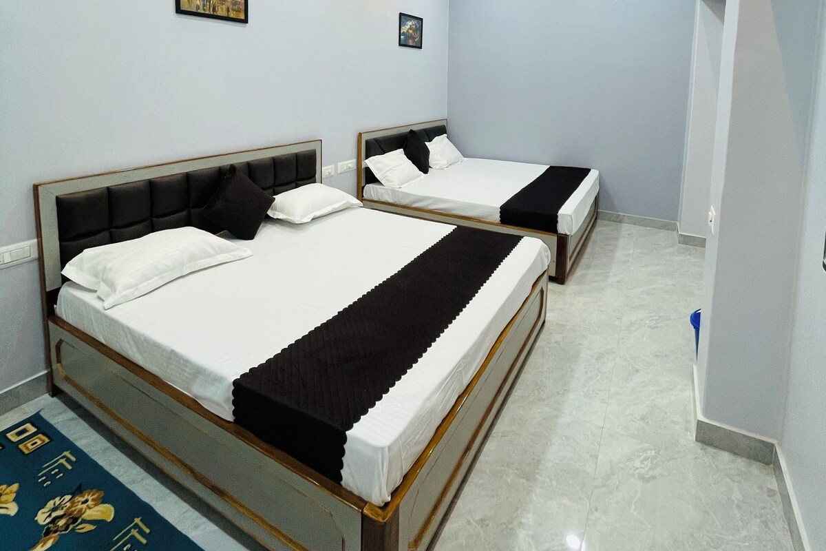 A hotel room with two beds, a ceiling fan, recessed lighting, and a wooden accent wall.