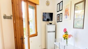 Un espacio habitable compacto con sofá, una mesa de comedor con sillas, un refrigerador y un televisor en la pared.