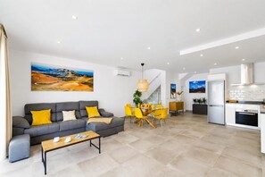 A modern living room with a sofa, coffee table, and dining area with chairs.