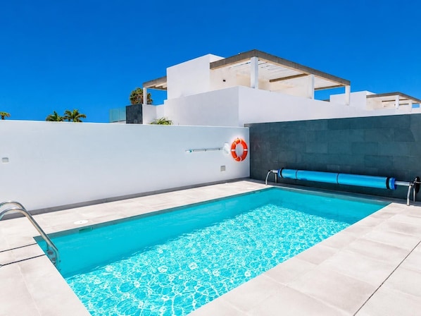 Piscina com uma boia, escada de metal e um escorregador azul.