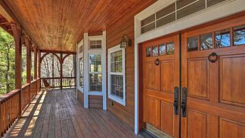 A wooden porch with a railing, large wooden garage doors, and a window with a lantern.