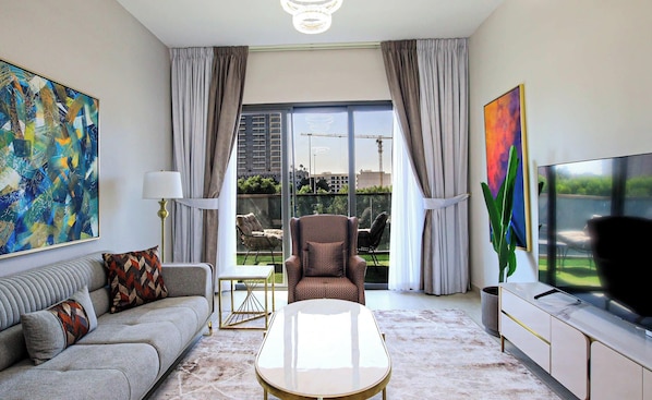 Un salon moderne avec un canapé, un fauteuil, une table basse et un téléviseur.